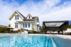 Svømmebasseng med hus og pergola i bakgrunnen