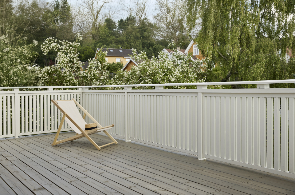Terrasse i lys gråtone beiset med TREBITT Terrassebeis i fargen TREBITT 90029 Naturlig Sølvgrå og rekkverk i hvitt malt i Jotun 1453 Bomull.