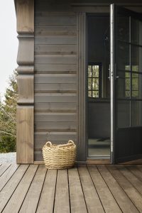 Detalj ved hyttevegg med åpen dør og kurv. Vegg beiset med Jotun TREBITT Matt Oljebeis Jenvitrol